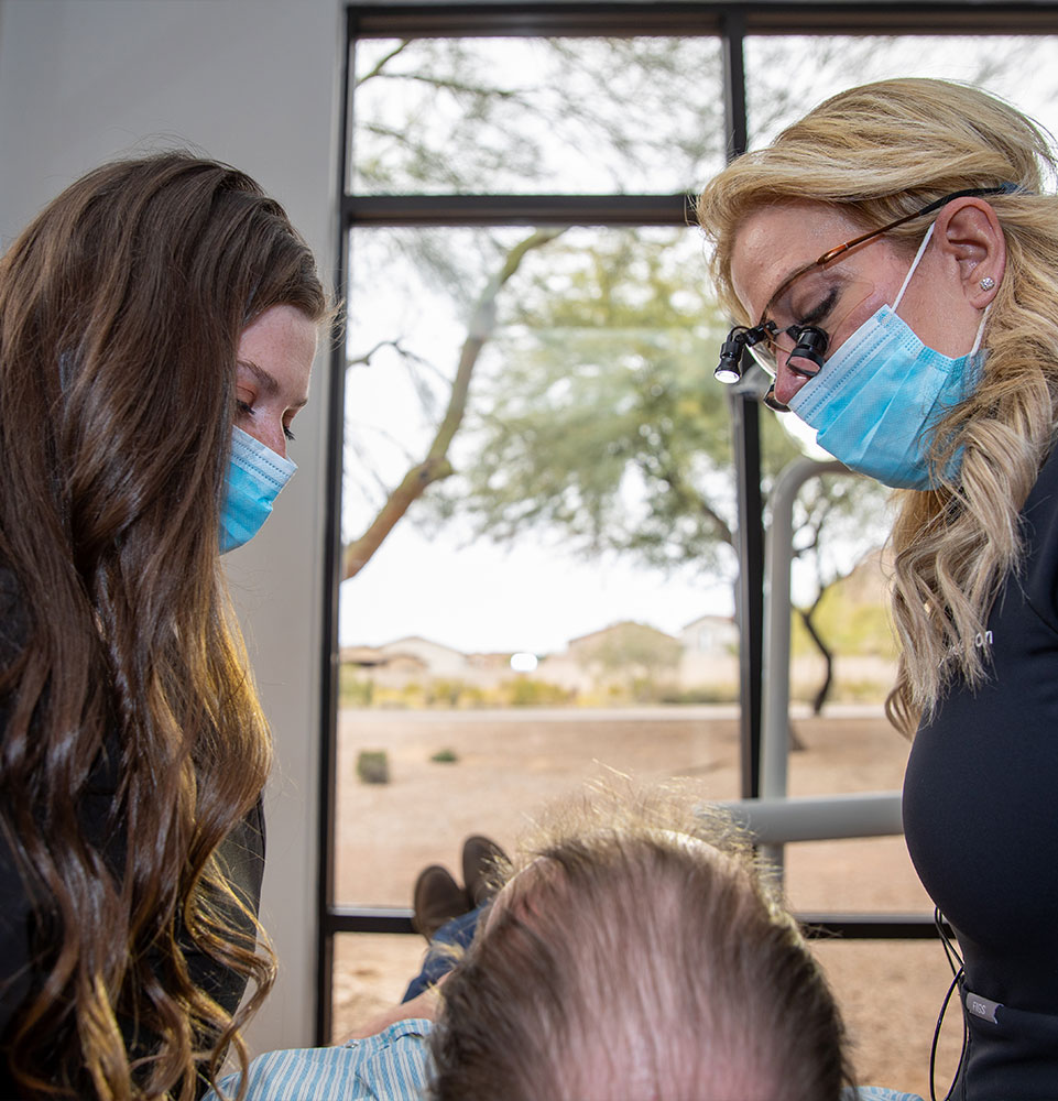 doctor and staff member examining dental patient for treatment