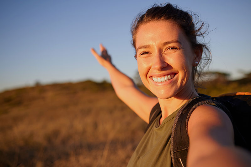 young woman taking a selfie while out hiking. smiling brightly with crowns