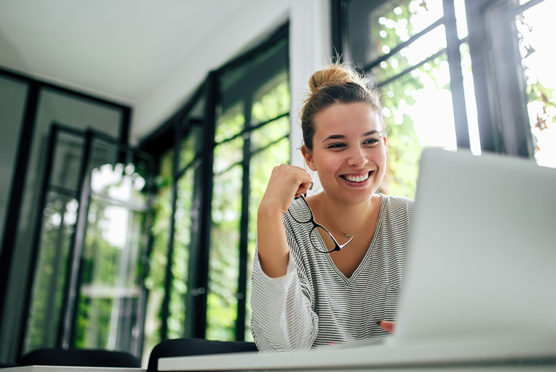 female smiling while using her laptop in the comfort of their own home