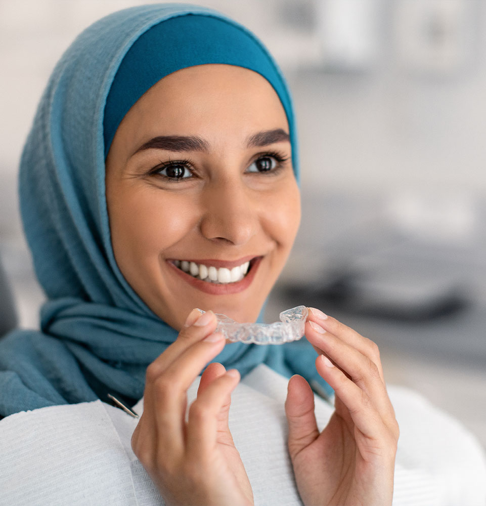 female smiling brightly while putting in their Invisalign