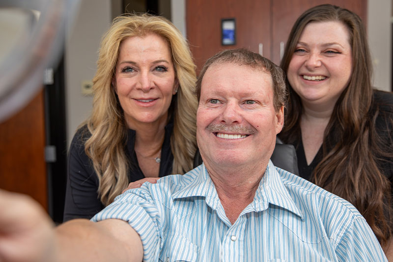 close up of patient doctor and staff member smiling brightly after patient dental procedure
